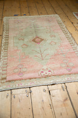 Distressed Oushak rug's bottom edge showing fringe and blush-toned primitive blossom motifs.