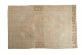 Vintage distressed Oushak carpet with a diamond medallion in soft cream, beige, and pale mint green.