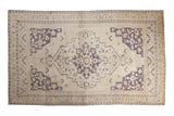 Distressed vintage Taspinar carpet, ivory field, dusty royal ink blue medallion, corner spandrels.
