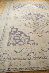 Detail of vintage Taspinar carpet, faded ivory with dusty blue dragon pattern.
