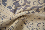Distressed texture and ivory, dusty blue geometric pattern on Taspinar carpet.