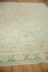 Distressed vintage Isparta rug close-up, featuring worn pale green palmettes and ivory floral pattern.
