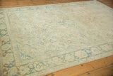 Distressed vintage Isparta rug showcasing faded ivory ground, soft pale green palmette border.