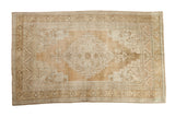 Hand knotted distressed vintage Oushak rug with central medallion and soft beige tones.