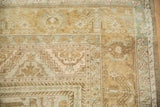 Distressed Oushak rug corner featuring worn muted gold, pale blue patterns and intact selvage.