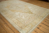 Distressed Oushak rug corner, showcasing faded patterns and soft fringe detail.