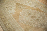 Close-up of distressed Oushak carpet with faded beige and pale blue floral design and worn pile.