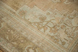 Muted green and beige botanical patterns on the distressed pile of this vintage Oushak.