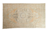 Distressed Turkish Oushak rug with a large medallion in muted terra cotta, sandalwood, and seafoam green.