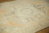 Distressed hand-knotted texture showing faded patterns in sandalwood, ivory, and seafoam green.