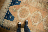 Corner of Vintage Distressed Oushak rug with stepped navy border and worn peach-toned pile.