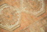 Textured pile showing soft peach and beige geometric motifs on a distressed Oushak rug.