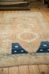 Distressed Oushak rug's time-softened blue stepped motif and machine-bound end.