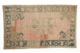 Vintage distressed Oushak rug with a center medallion, pale rose field, and dusty teal border.