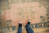 A personal perspective of a distressed Oushak rug's soft rose and teal colors underfoot.