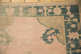 Corner detail of a distressed Oushak rug with a dusty teal and beige floral spandrel.
