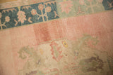 Textured hand-knotted pile with abrashed pinks and a dusty blue floral border.