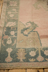 Worn hand-knotted texture of a vintage Oushak rug's corner spandrel in dusty teal and rose.