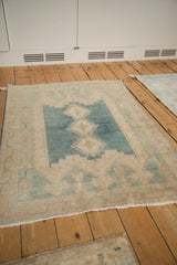Worn texture of a vintage Isparta rug, with faded blue and ivory geometric motifs.