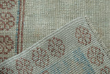 Corner of a distressed Oushak rug showing the hand-knotted back and low, worn pile texture.