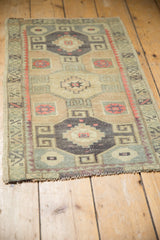 Full-length perspective of a distressed vintage Kars rug with triple geometric medallions.