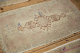 Close-up of distressed Oushak rug mat pile, with faded ivory and mauve ram's horn motifs.