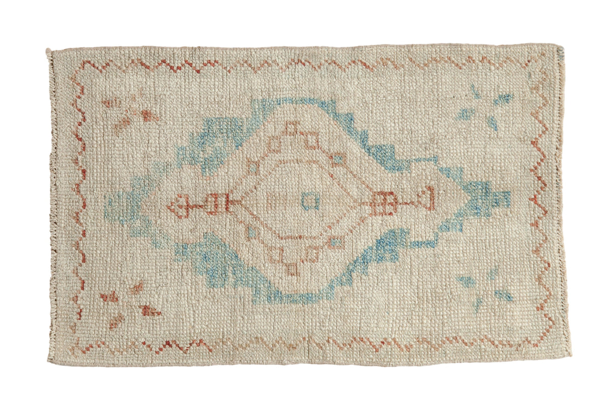 Distressed Oushak rug with a large geometric medallion in sky blue and copper on a textured ivory field.