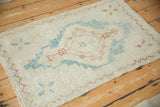 Angled view of a distressed Oushak rug showing its even, low-pile wear and geometric pattern.