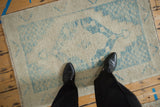 Textured close-up of the distressed Oushak rug's low pile with visible ivory and blue knot heads.