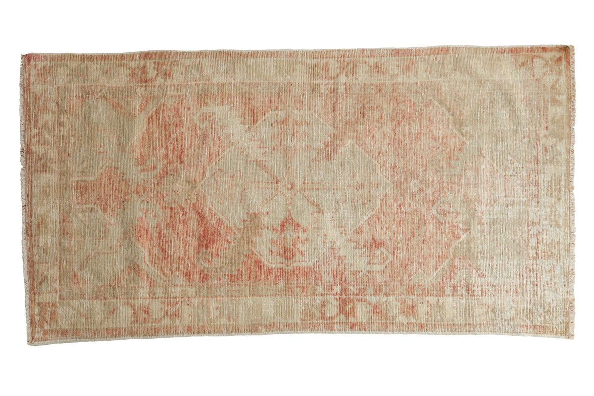 Vintage distressed Oushak rug with a faded diamond medallion in soft blush and ivory tones.