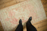 A vintage distressed Oushak rug runner viewed from above to show its scale and soft, worn texture.