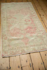 Angled view down the length of a vintage distressed Oushak runner with a soft blush and ivory palette.