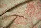 A close-up view of the vintage Oushak rug's distressed, low pile in soft blush and ivory tones.