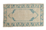 Distressed vintage Oushak rug with a central sky blue cartouche medallion and stylized border.