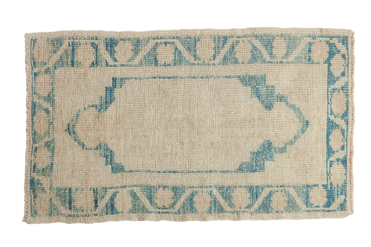 Distressed vintage Oushak rug with a central sky blue cartouche medallion and stylized border.