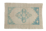 Distressed Oushak rug with a blue starburst medallion and spandrels on an antique ivory, low-pile field.