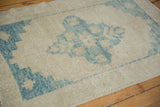 Textured low pile of a distressed Oushak rug with sky blue motifs on an antique ivory ground.