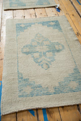 Angled view of a distressed Oushak rug showing its low pile and blue medallion on a platinum field.