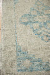 Detail of the distressed Oushak rug's texture, with low knot heads in antique ivory and sky blue.