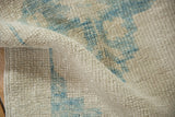 The distinct texture of a hand-knotted Oushak rug with visible knot heads in ivory and sky blue.