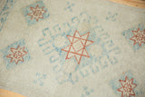 Geometric starburst and hook designs in copper and powder blue on a distressed Oushak rug.
