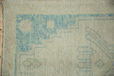 Distressed Oushak rug detail: visible pile wear with powder blue geometric patterns.