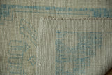 Distressed Oushak rug with low platinum and powder blue pile, showing even wear and hand-knotted woven back.