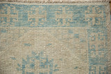 Distressed Oushak pile with worn powder blue and antique ivory geometric pattern, plus fringe.