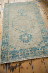 Distressed Oushak rug showing low pile texture and faded powder blue medallion details.