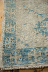 Distressed texture, even wear, and powder blue geometric border of an Oushak runner.