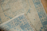 Distressed Oushak runner's texture showing blue geometric pattern, knot heads, and side selvage.