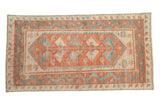 Distressed Oushak rug runner with a floral vine pattern in cinnabar red, sky blue, and ivory.