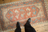 A standing perspective of a distressed Oushak runner, showing its scale and red and blue pattern.