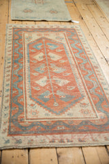 Angled view of a distressed Oushak runner with cinnabar red and sky blue hues.